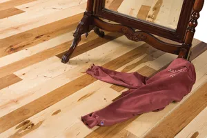 A wooden chair and a folded red cloth on a light hardwood floor with contrasting dark planks