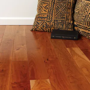 A reddish-brown hardwood floor with patterned cushions against the wall