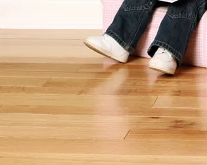 A child in jeans and white sneakers sitting on a stool over a light hardwood floor